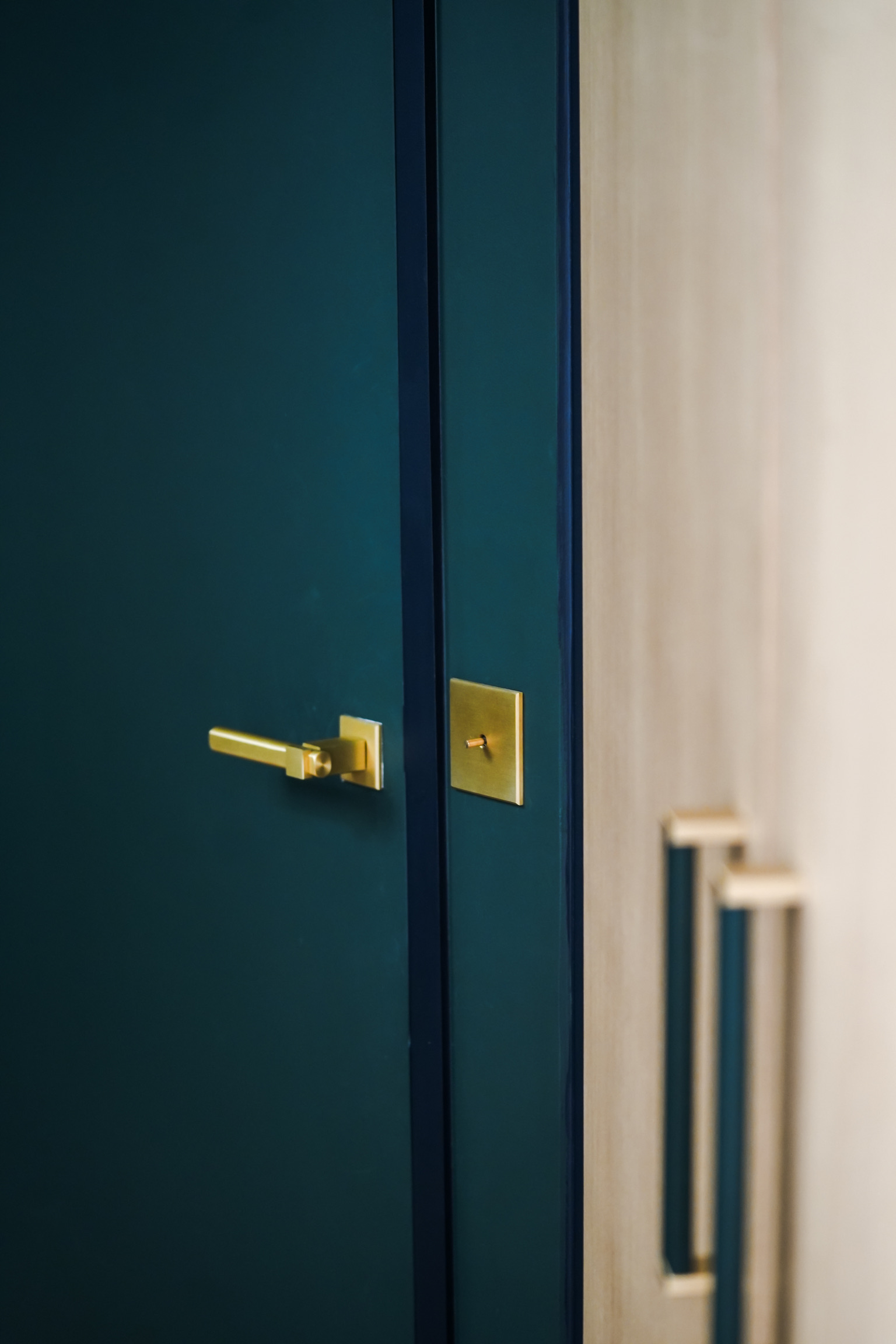 Appareillage en laiton Matière Lumière sur une porte bleue